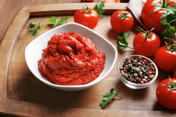 Delicious tomato paste in bowl with ingredients on tray, closeup
