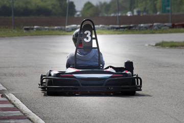 man drive go kart on track back view