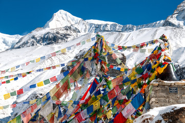 Buddyjskie flagi modlitewne w Annapurna Base Camp na tle ośnieżonych gór.