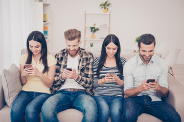 Modern life. Four young friends in jeans and casual shirts are browsing info in apps like social networks, using wi fi. Ethnicity and multicultural company, such a diverse