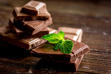 black and milk chocolate bars with mint dark wooden table background