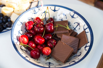 Cherry and milk chocolate in the plate, bowl with anchors. Nautical style