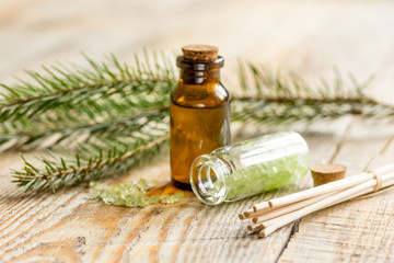 fir branches and spruce bath salt and aroma oil on wooden table background