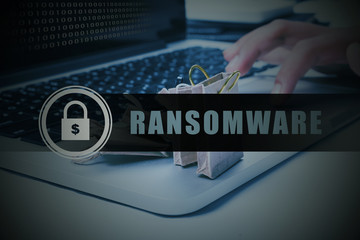 Binary code on laptop screen with finger clicking mouse pad trying to retrieve folder by paying ransom to hacker. Security technology concept.