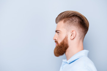 Advertising barbershop concept. Profile side portrait of confident handsome red bearded young man. He has a perfect stunning hairstyle, modern haircut