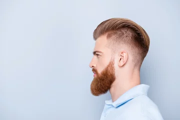 Tuinposter Advertising barbershop concept. Profile side portrait of confident handsome red bearded young man. He has a perfect stunning hairstyle, modern haircut © deagreez