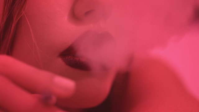 Woman smoking cigarette. Cigarette in sexy woman lips. Woman smoke cigarette and blow smoke. Close up girl exhales smoke from mouth. Inhales cigarette smoke with plump sexy lips