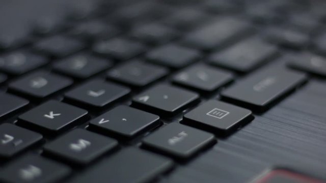 Close up move left to right over back lit laptop keyboard with red pulsing nahimic RGB keys flashing side to side 