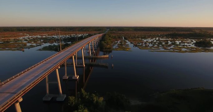 An early morning sunrise reverse aerial establishing shot of the Topsail Island Bridge over the Intracoastal Waterway.	 	