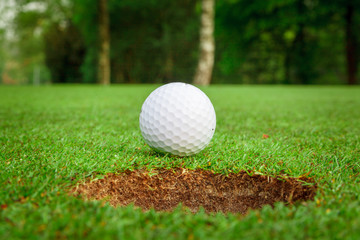Golf ball on green meadow. golf ball on lip of cup