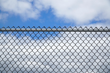 iron chainlink fence against sky - Powered by Adobe