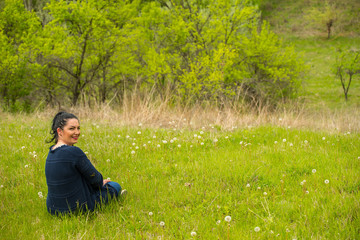 Smiling woman sits in spring grass