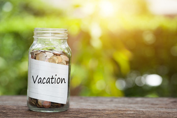vacation word with coin in glass jar on wooden table.