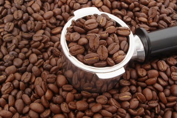 Roasted coffee beans withcoffee maker portafilter on coffee background