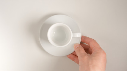 TOP VIEW: Human hand puts a white coffee cup on a white table