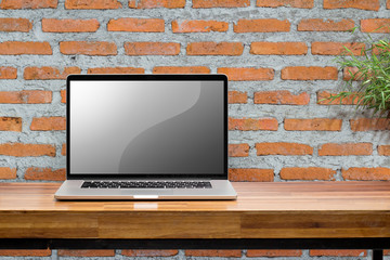 Laptop blank screen on wooden table with red brick wall background / clipping mask
