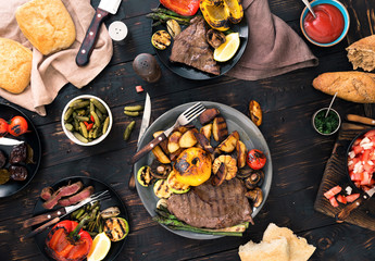 grilled steak and grilled vegetables on dark wooden table