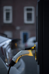 View of an Electric Car Charging Column at twilight and in the background a partial view of a white...