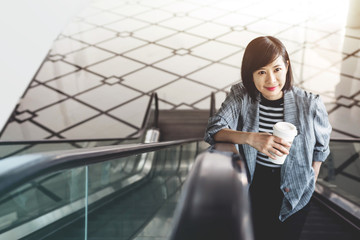 Attractive and confident working woman with coffee cup at Escalator inside building, Social communicate technology in business concept, Urban Lifestyle of modern female © blacksalmon