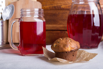 Fresh and healthy red Fruit juice drink  in a glass and jug and muffin or cake on the wooden brown table background. Side view.