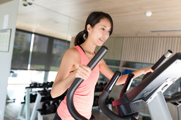 Fototapeta na wymiar Woman training on Elliptical machine in gym