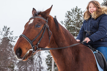 Girl teenager and big horse in a winter