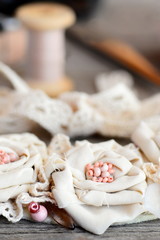 Shabby chic flowers necklace from cotton fabric, lace trims, beads and felt base on a wooden background. Summer fabric jewellery. Hand flowers necklace. Art to wear. Vertical photo. Closeup