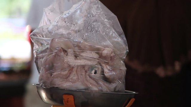 Squid in a bag is weighed in the local fish market
