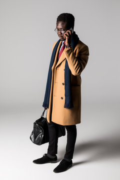 Full Length Side Portrait Of Young African Businessman Using Mobile Phone Isolated