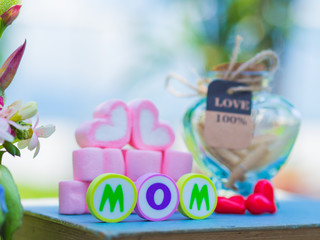 mother's day concept. MOM alphabet with marshmallow in the shape of heart and flower on background