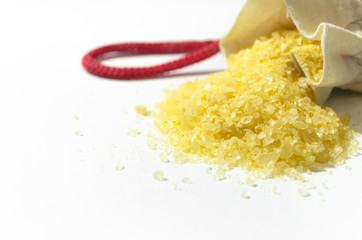 Bath salt spilled from a small bag close up isolated on white background.