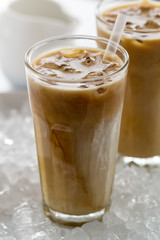 Tasty cold refreshing drink with coffee, milk and ice in glass on ice background. Closeup.