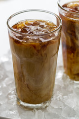 Tasty cold refreshing drink with coffee, milk and ice in glass on ice background. Closeup.