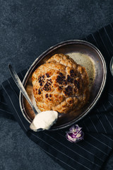 Whole roasted cauliflower with goat cheese sauce on metallic tray on dark rustic background with vintage spoon