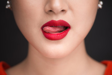 Beauty. Close up view of beautiful woman lips with red matt lipstick licking her desire - obrazy, fototapety, plakaty