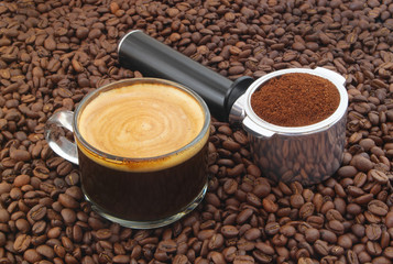 Cup of hot coffee with ground coffee in espresso machine portafilter on roasted 