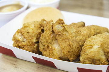 Closeup of fried chicken drumsticks meal on white paper plate.