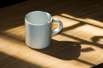 Lighting from window with white coffee cup on the wooden.
