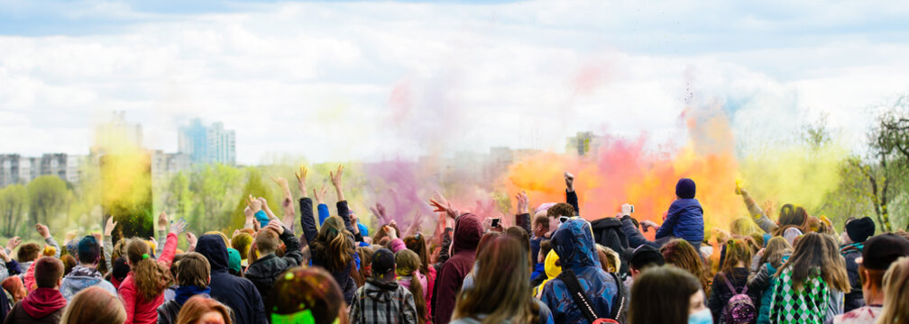 Holiday holi, young people in smoke dancing hands up outdoors