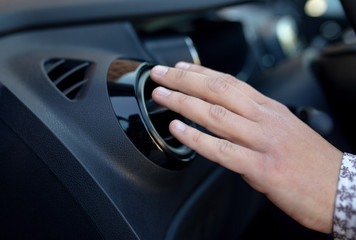 Driver hand on air ventilation grille with power regulator, modern car interior detail