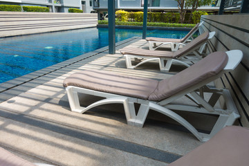 Relaxing rattan chairs and bed beside swimming pool with light ans shadow