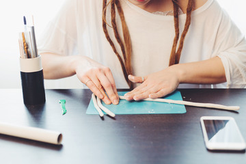 Woman's hands mold out of clay on wooden table