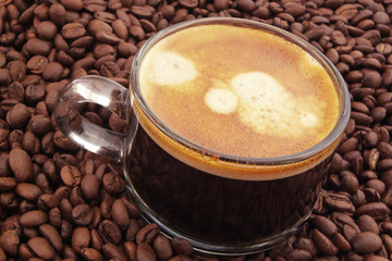 Cup of espresso coffee on roasted coffee beans background