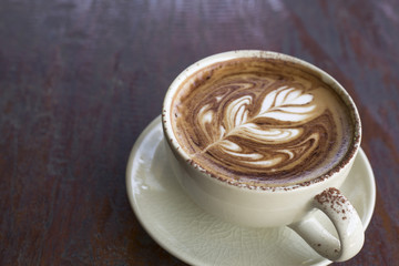 Cappuccino sprinkled with cocoa powder on old wooden table
