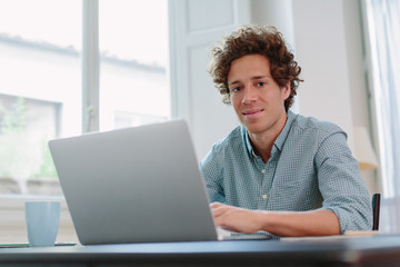 Happy young man working with computer from home