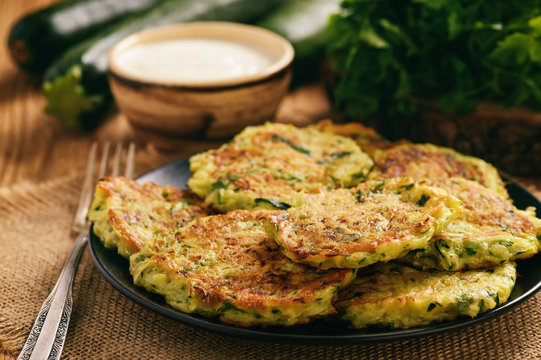 Vegetarian food - zucchini fritters on wooden background.