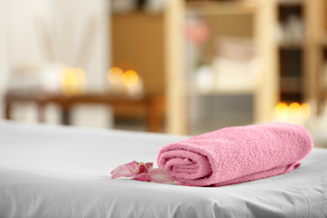 Towel and flower on massage table in modern spa salon