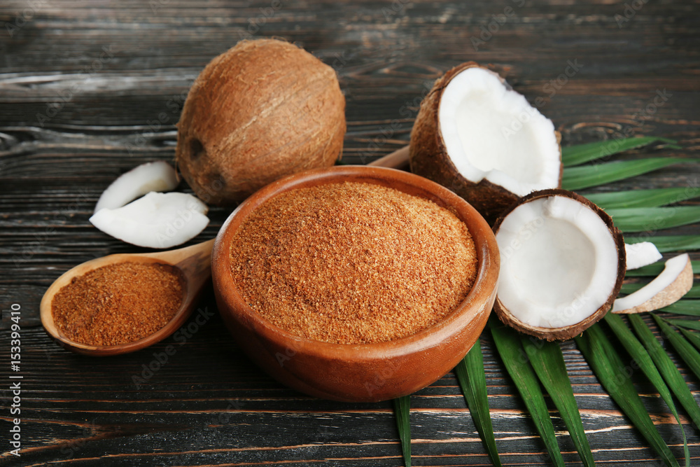 Wall mural bowl and spoon of brown sugar with coconut on wooden background