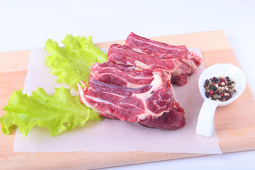 Raw beef edges, lettuce leaf and spices on wooden desk isolated on white background from above and copy space. ready for cooking.