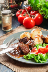 Pork meat stew served with potatoes and vegetable salad
